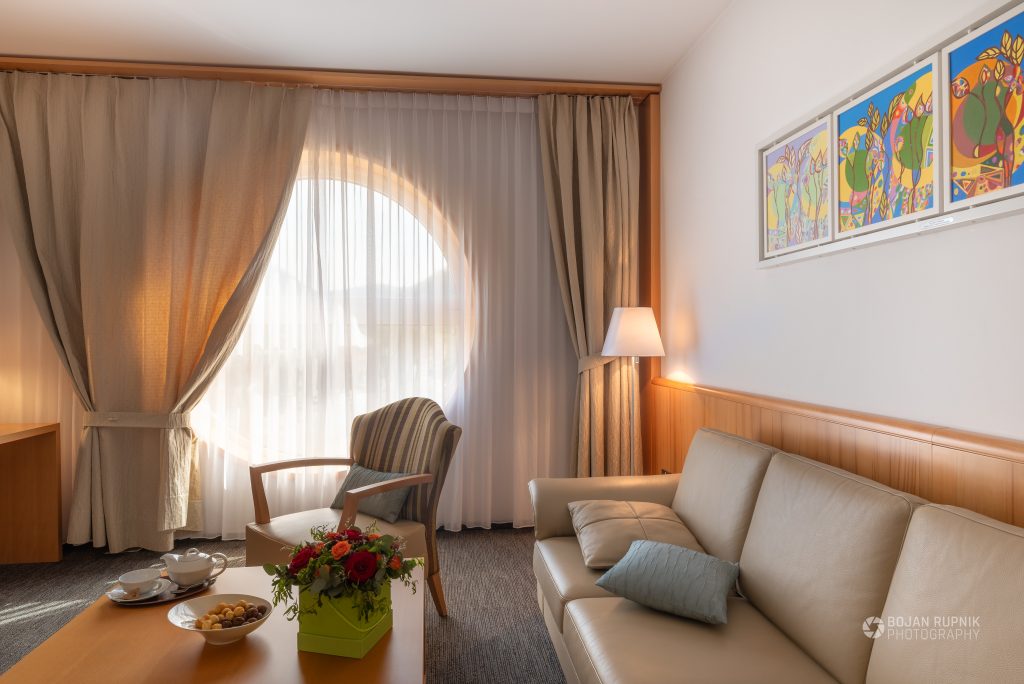 Hotelska soba s stolom, kavčem in sobno lučko
