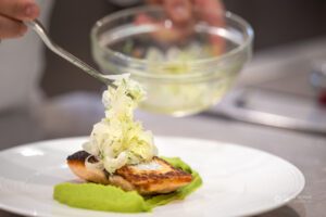 Kuhar dekorira pečenega lososa s ribano zeleno