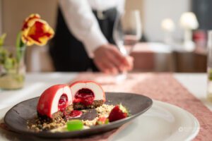 Na pol prerezana sladica z rdečo marmelado v sredici in natakarjem v ozadju